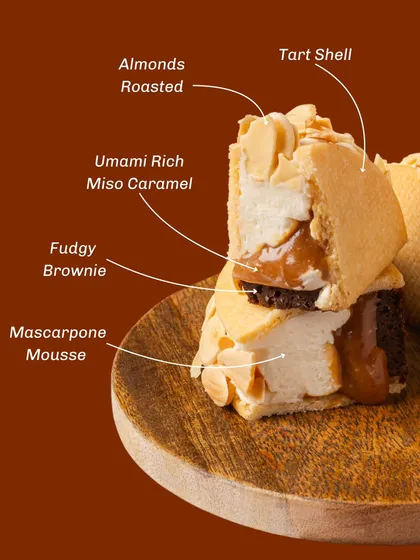 This is a look inside our Miso Caramel Tart. It features a unique combination of a fudgy brownie base, mascarpone mousse, and an umami-rich miso caramel, all encased in a crisp tart shell. It’s one of our more adventurous gourmet desserts.