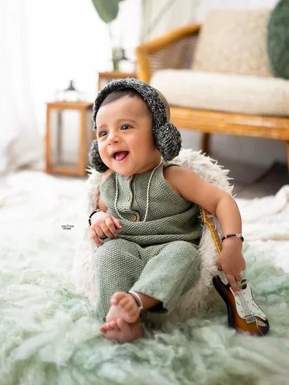 A happy little musician with his guitar and earmuffs.