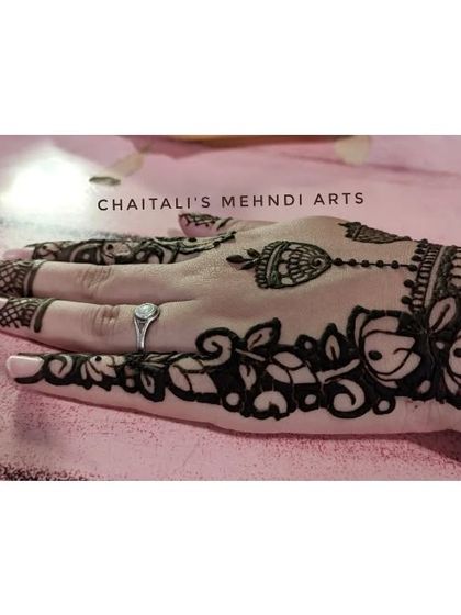 This is a modern and elegant design for the back of the hand, featuring a floral vine and a hanging jhumki motif. This 'cutwork' style leaves negative space for a bold effect.
