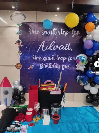 Take your party to another galaxy with a space-themed setup. This decoration for a 5th birthday features a cosmic backdrop, planet and astronaut cutouts, a rocket prop, and a light-up number '5' to create an out-of-this-world adventure.