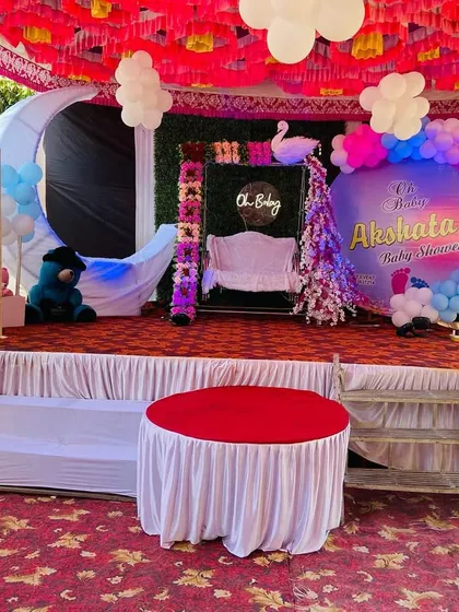 A complete stage setup for a baby shower, including a moon prop, swing, and a personalized backdrop with the mother's name.