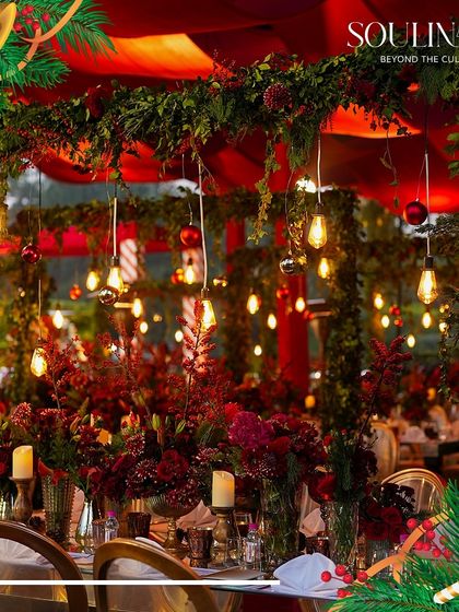 A festive Christmas celebration with tables adorned in rich red decor, garlands, and ambient lighting. We create magical holiday experiences with our themed catering and decor.