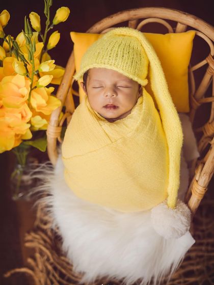 A pop of sunshine for this little man. The bright yellow wrap and matching sleepy cap create a cheerful and heartwarming portrait.