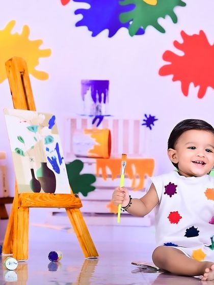 A happy little artist smiling proudly next to their masterpiece. The colorful setup makes for a vibrant and cheerful photo.