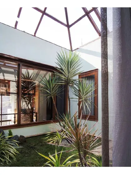 A view into one of the internal courtyards that give the 'Aangan' house its name and character. Topped with a skylight, this green space acts as the lungs of the home, providing natural light, fresh air, and a constant visual connection to nature for the surrounding rooms.