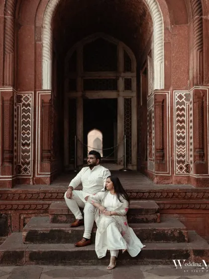 An elegant portrait of the couple seated on the steps of the Taj Mahal complex. The composition is classic and regal, perfectly suited to the majestic location.