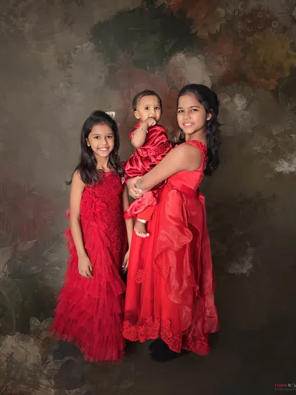 The sister bond is forever. These three sisters look beautiful in their matching red dresses, creating a classic and elegant portrait.