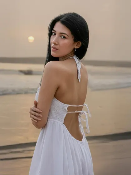 A serene golden-hour portrait of a woman on a beach, looking over her shoulder with the sun setting over the ocean. This image highlights my ability to capture natural beauty and emotion in outdoor settings.