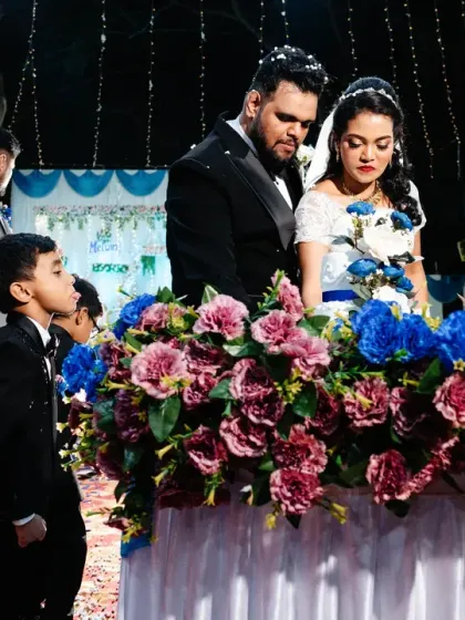 A little boy watches intently as the couple cuts their wedding cake.