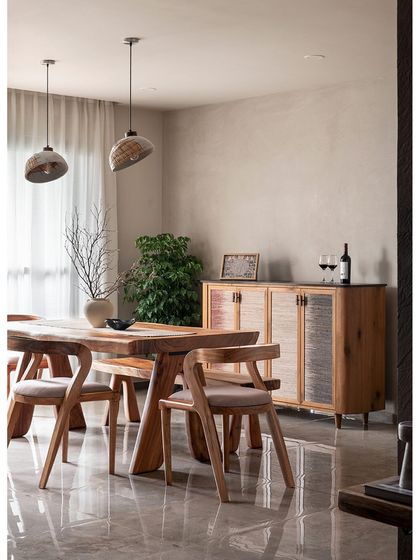 This dining room showcases a Wabi-Sabi aesthetic with its limewash wall and banana fibre-finished crockery console. The custom live-edge dining table and chairs bring an organic, natural feel to the space.
