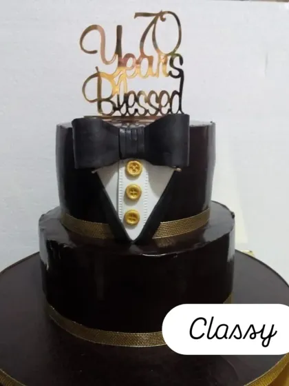 A sophisticated two-tiered tuxedo cake for a 70th birthday. The rich chocolate ganache finish and gold button details add a touch of class.