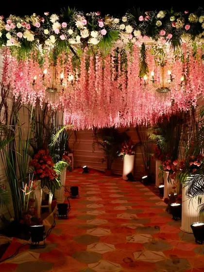 This enchanting entrance was created with a ceiling of hanging pink wisteria. The floral canopy, combined with soft lighting, provided a warm and romantic welcome for guests as they arrived at the wedding celebration.