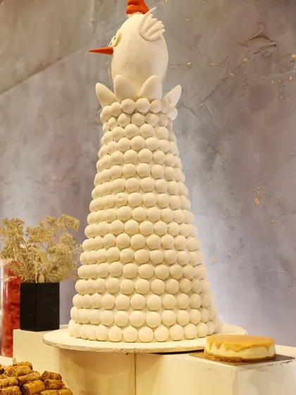 A whimsical dessert tower made of white macarons, topped with a charming bird figure. We love adding playful touches to our elegant spreads.