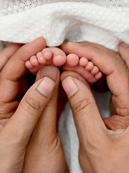 The whole world in their hands. This close-up of a newborn's tiny feet held gently by mom and dad is a powerful reminder of how small they start. These are the details you will want to remember forever.