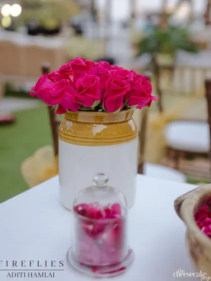 A simple centerpiece of bright pink roses in a traditional ceramic 'barni' jar, a classic and timeless decor choice.