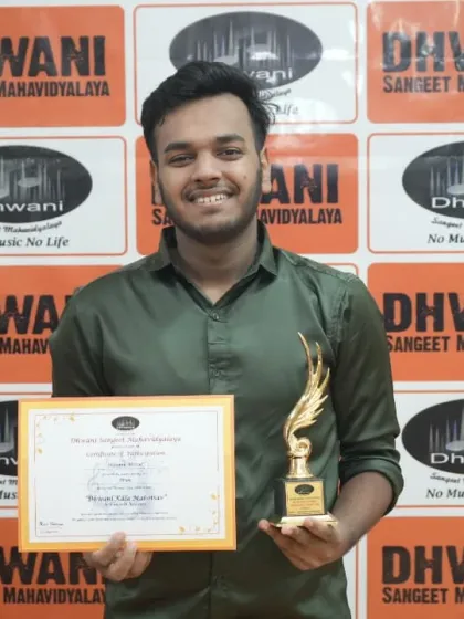 A smiling student proudly displays his certificate and trophy.