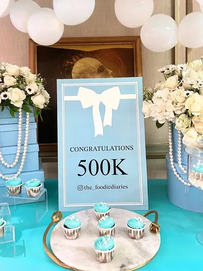 To celebrate a 500k milestone, we designed a surprise "Breakfast at Tiffany's" themed party, using the iconic Tiffany blue, white florals, pearls, and a custom dessert cart.