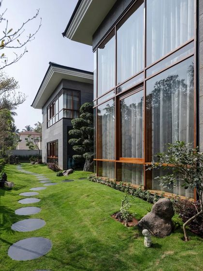 The home's large, floor-to-ceiling windows offer expansive views of the manicured lawn and garden.