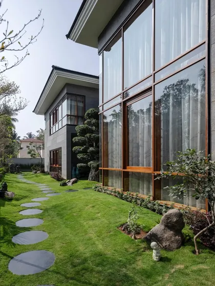 The home's large, floor-to-ceiling windows offer expansive views of the manicured lawn and garden.