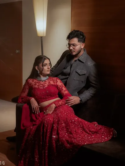 A moody and romantic portrait of the couple on their Sangeet night, dressed in stunning red and grey ensembles.