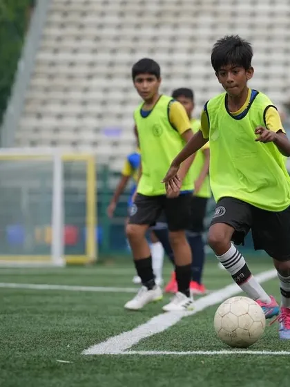 A U14 squad member dribbles the ball with speed and control down the sideline. This dynamic shot showcases the agility and technical skill we develop in our youth players.