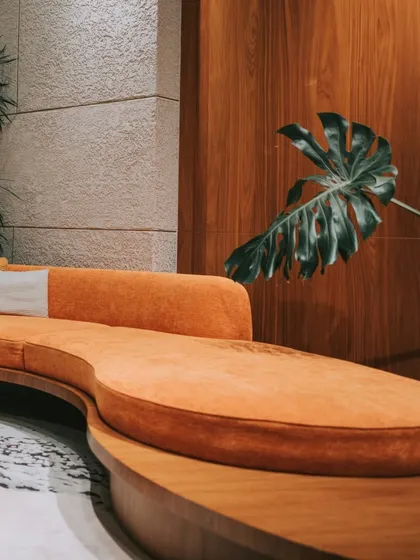 A close-up of the custom-designed curved sofa in a lobby. The vibrant orange fabric and organic shape provide a comfortable and visually striking seating solution that makes a lasting impression.