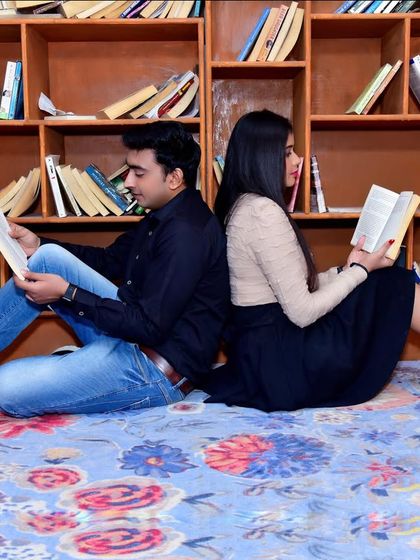 Another angle from the library-themed pre-wedding shoot, showing the couple engrossed in their books, back to back.