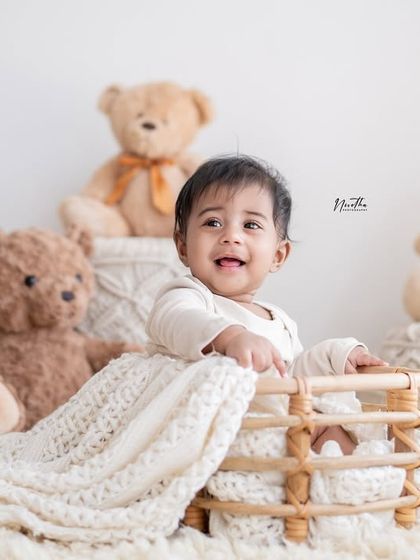 A cozy teddy bear-themed shoot on a fluffy white rug. The neutral colors and soft textures make for a very sweet portrait.