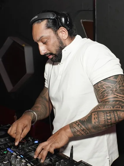 A close-up of me working the mixer, showing my tattooed arm. My personal style is part of my brand, bringing a cool and modern edge to my performance.