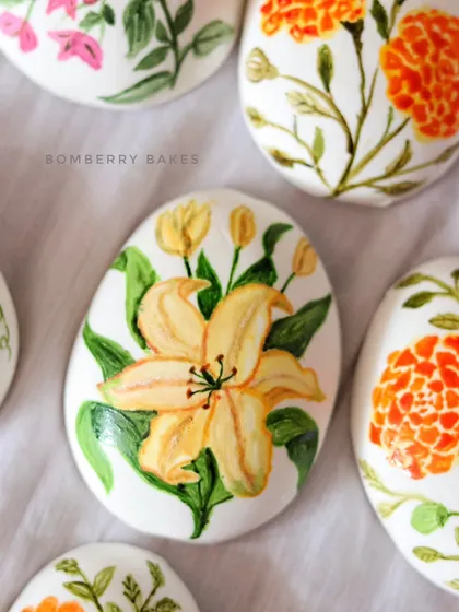 A close-up of a marzipan egg with a beautifully painted yellow lily.