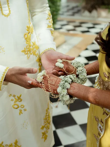 A symbolic shot of the couple holding hands, showcasing the intricate mehendi and beautiful floral bracelets.