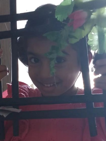 A happy child peeks through the photo frame she made herself during a summer camp craft session. It's a wonderful take-home memory.