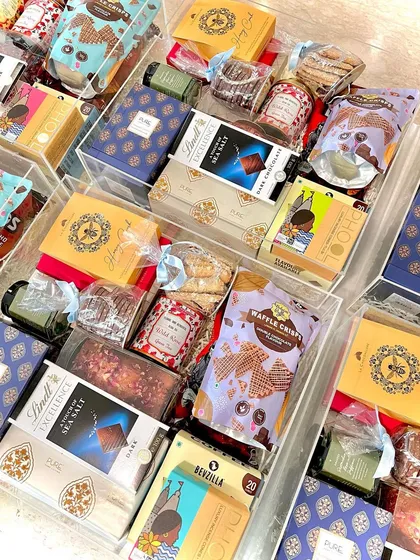 For those looking for ultimate luxury, I create exquisite hampers in these clear acrylic trunks. This one is filled with premium treats from brands like Ladurée and Lindt, scented candles, and other lavish goodies to truly wow your special guests.