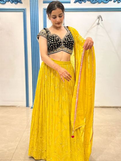 This vibrant yellow lehenga with a contrasting embroidered black blouse is a modern and chic Haldi outfit.