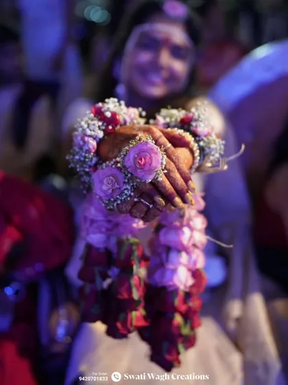 A close-up of the bride holding her floral kalire. The combination of fresh roses and baby's breath is a classic and romantic choice.