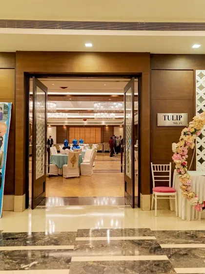The entrance to the party hall is the first impression. Here, I set up a custom photo collage standee showing the family's journey, along with a beautiful floral ring for guests to take pictures as they walked in.