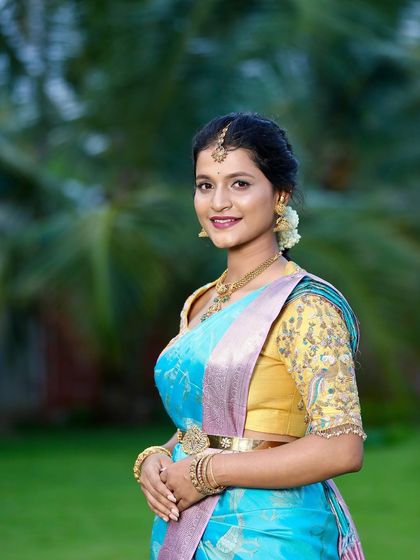 The beautiful bride-to-be Kavya glows in a sky-blue designer silk saree for her engagement. Paired with a contrasting yellow embroidered blouse, this look is both vibrant and traditionally elegant.