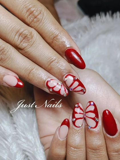 A creative and romantic butterfly wing design in a bold red. The wings are spread across two nails and accented with tiny rhinestones for a touch of sparkle.