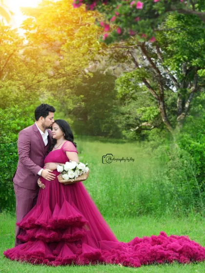 A tender moment between expecting parents, captured in our private outdoor garden. The vibrant magenta gown stands out beautifully against the lush greenery, and the golden hour light adds a warm, romantic glow to this pregnancy portrait.