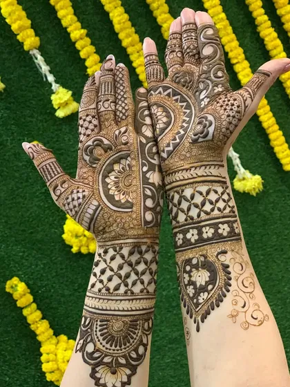 This full bridal design is set against a festive backdrop of marigold flowers. The artwork features a mix of traditional Indian motifs, including paisleys, florals, and checkerboard patterns.