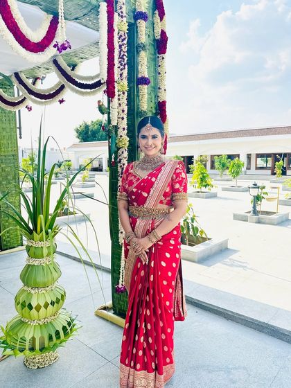A shot of me at an outdoor event, my red saree looking vibrant against the green backdrop.
