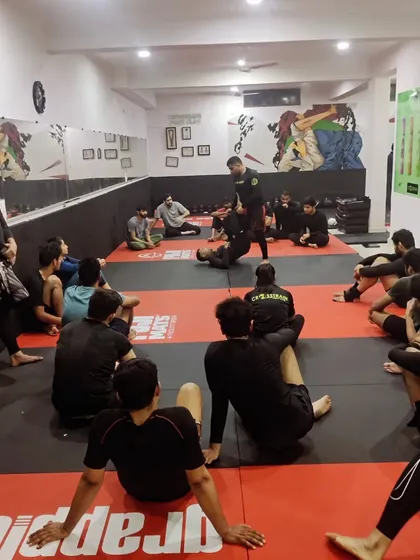 There are no shortcuts to success. A coach demonstrates a guard pass to a focused group of students during a Jiu-Jitsu session.