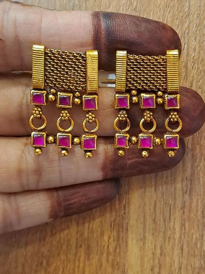 A unique pair of antique gold-plated earrings with a mesh design and pink stone drops. They are a modern take on traditional jewelry.
