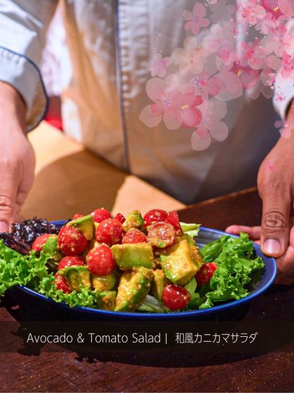 A chef presents the Avocado and Tomato Salad. The creaminess of the avocado pairs perfectly with the sweetness of the cherry tomatoes and the savory dressing.