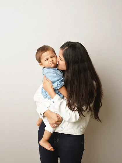 A mother kisses her son, who makes a funny, scrunched-up face. It's these quirky, real moments that truly capture a child's personality.