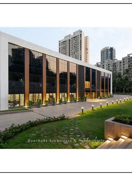 The exterior of a modern office building we designed in collaboration with Studio Agara. The facade combines glass, wood paneling, and clean white forms, with landscape lighting that enhances its appearance after dark.