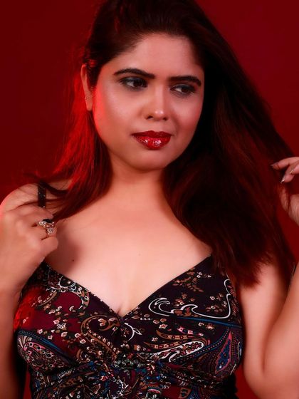 A close-up beauty shot with a focus on her glamorous red lip and thoughtful expression.