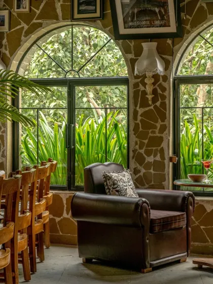 This seating area at Echoes captures the essence of Himalayan serenity. The combination of a comfortable leather armchair, rustic stone walls, and large arched windows framing the outdoors offers a tranquil escape from the city.