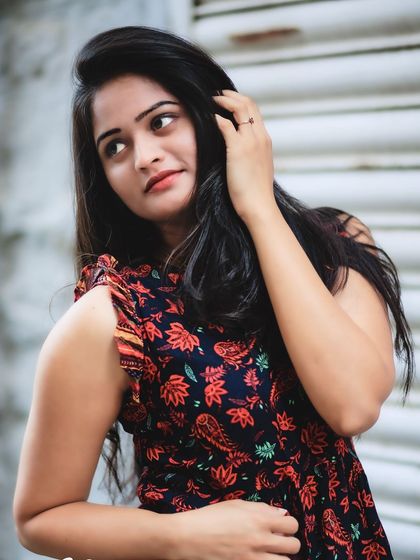 A vibrant outdoor portrait. The pop of color from her floral dress against the neutral background is eye-catching and full of life.