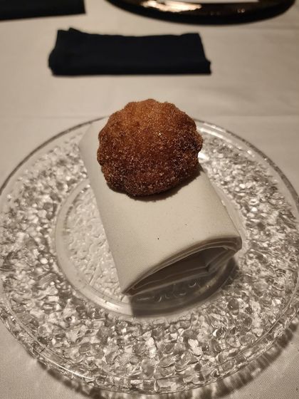 A single, perfect bitterballen, a Dutch-inspired croquette filled with a creamy chicken confit, resting on a folded napkin.